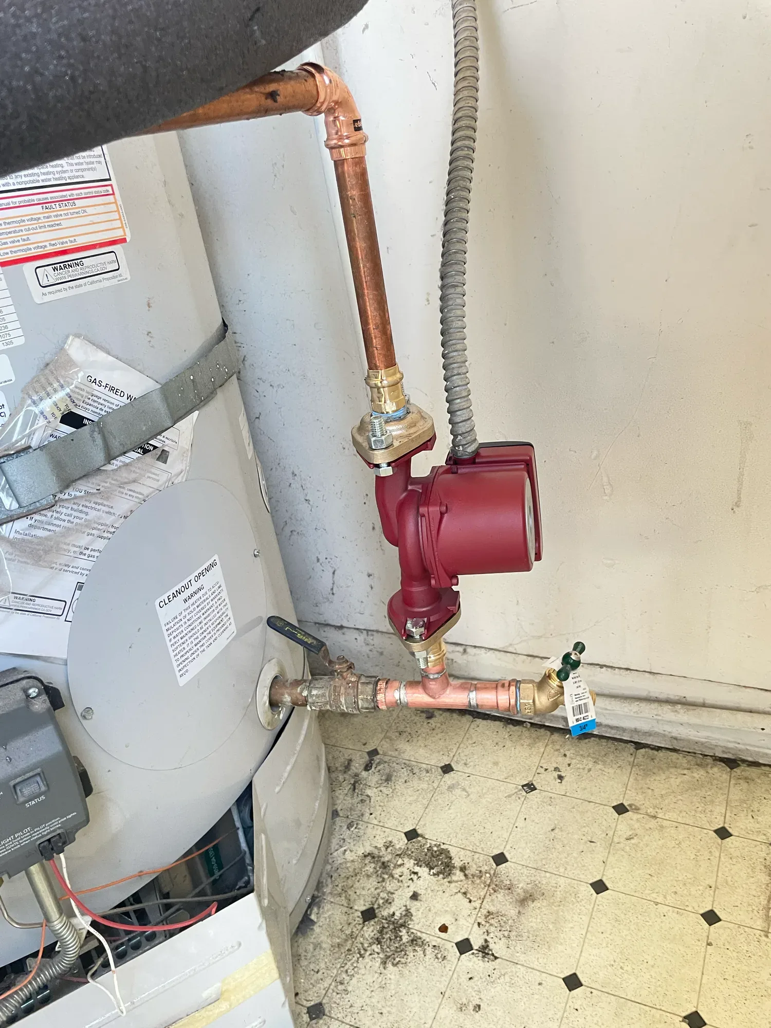 Copper piping and a red circulation pump connected at the base of a tank water heater