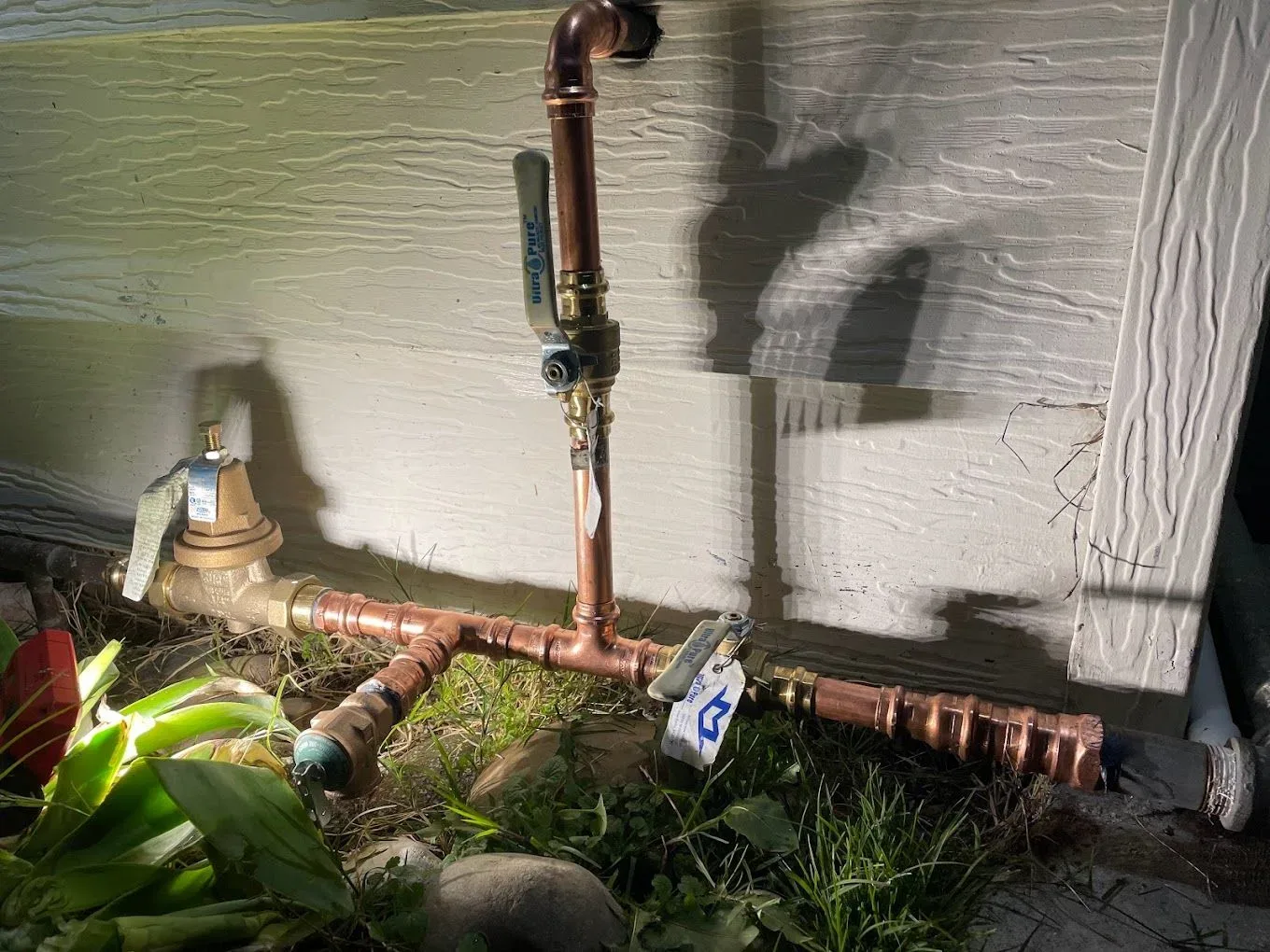 New copper manifold with a pressure regulator and shutoff valves along an exterior wall