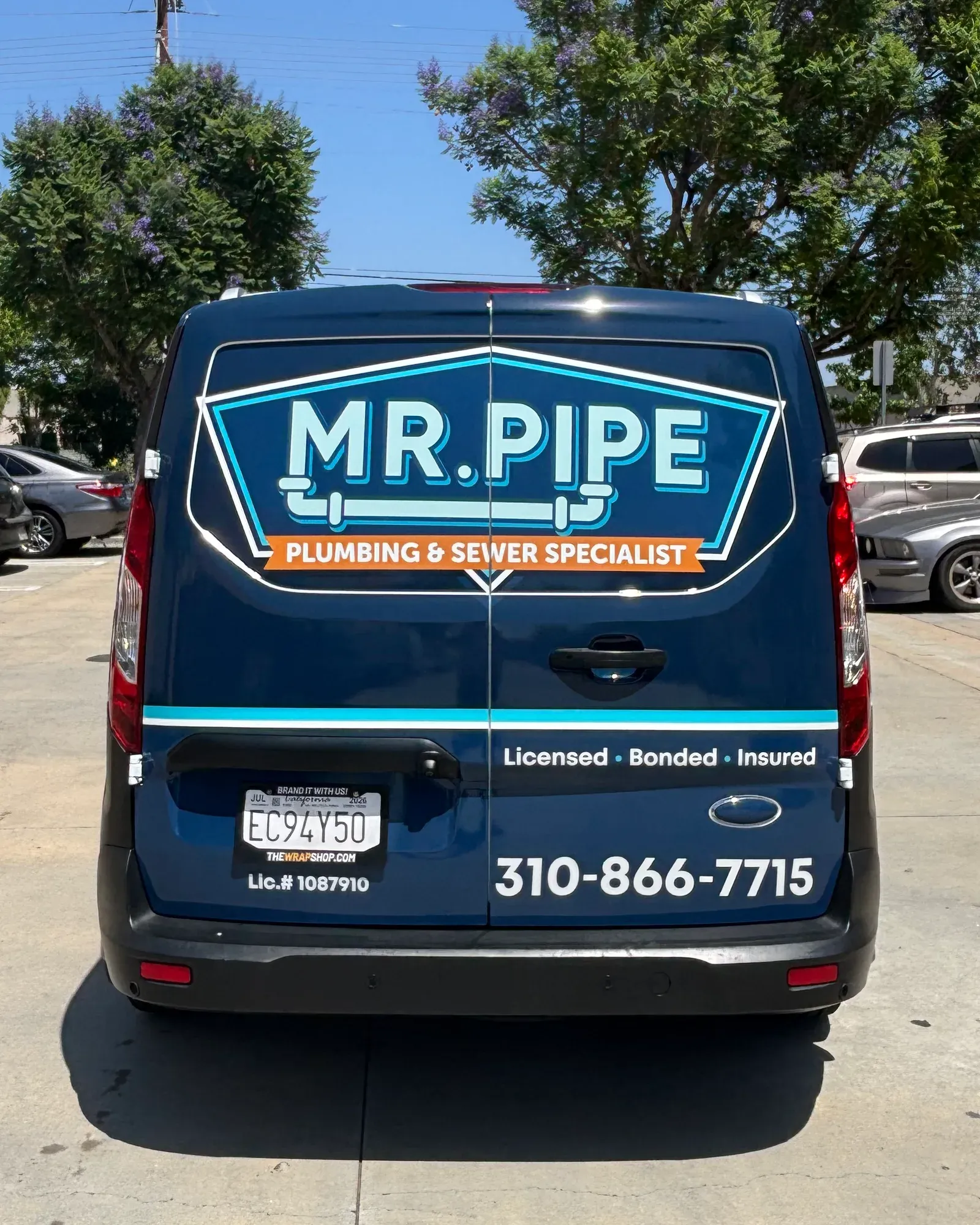Rear of a marked Mr. Pipe Plumbing service van showing the company name and phone number