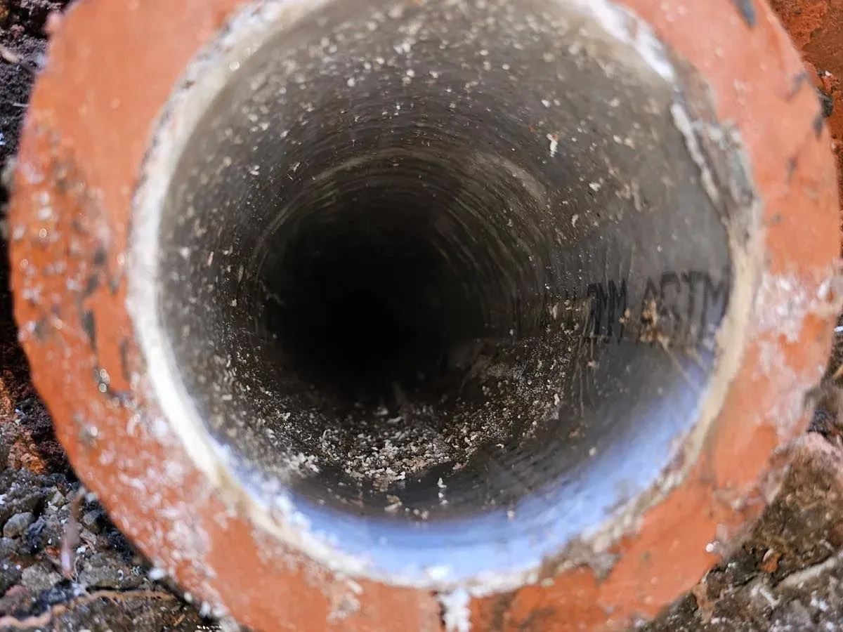 The cut end of a clay sewer pipe with a new liner cured inside it, seen down the bore