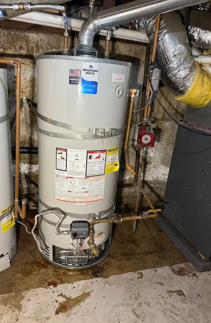 Gas tank water heater held to the wall by two seismic straps, with its vent pipe and gas valve
