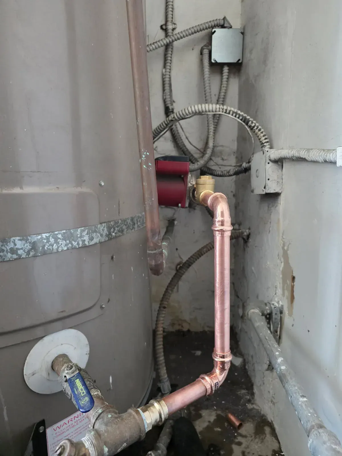 New copper line and circulation pump connected to a strapped tank water heater