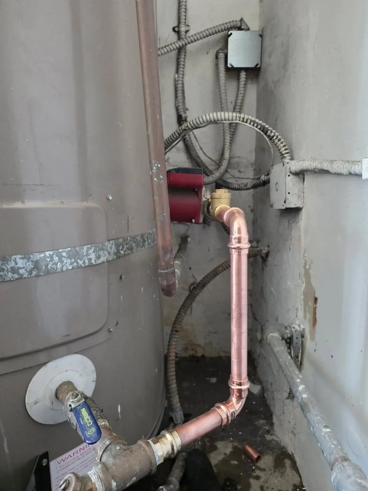 New copper line and circulation pump connected to a strapped tank water heater